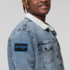 Man wearing jean jacket with embroidered Apex Interstellar Transport logo in blue right view