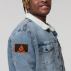 Man wearing jean jacket with embroidered Bank of Zaonce logo in orange right view