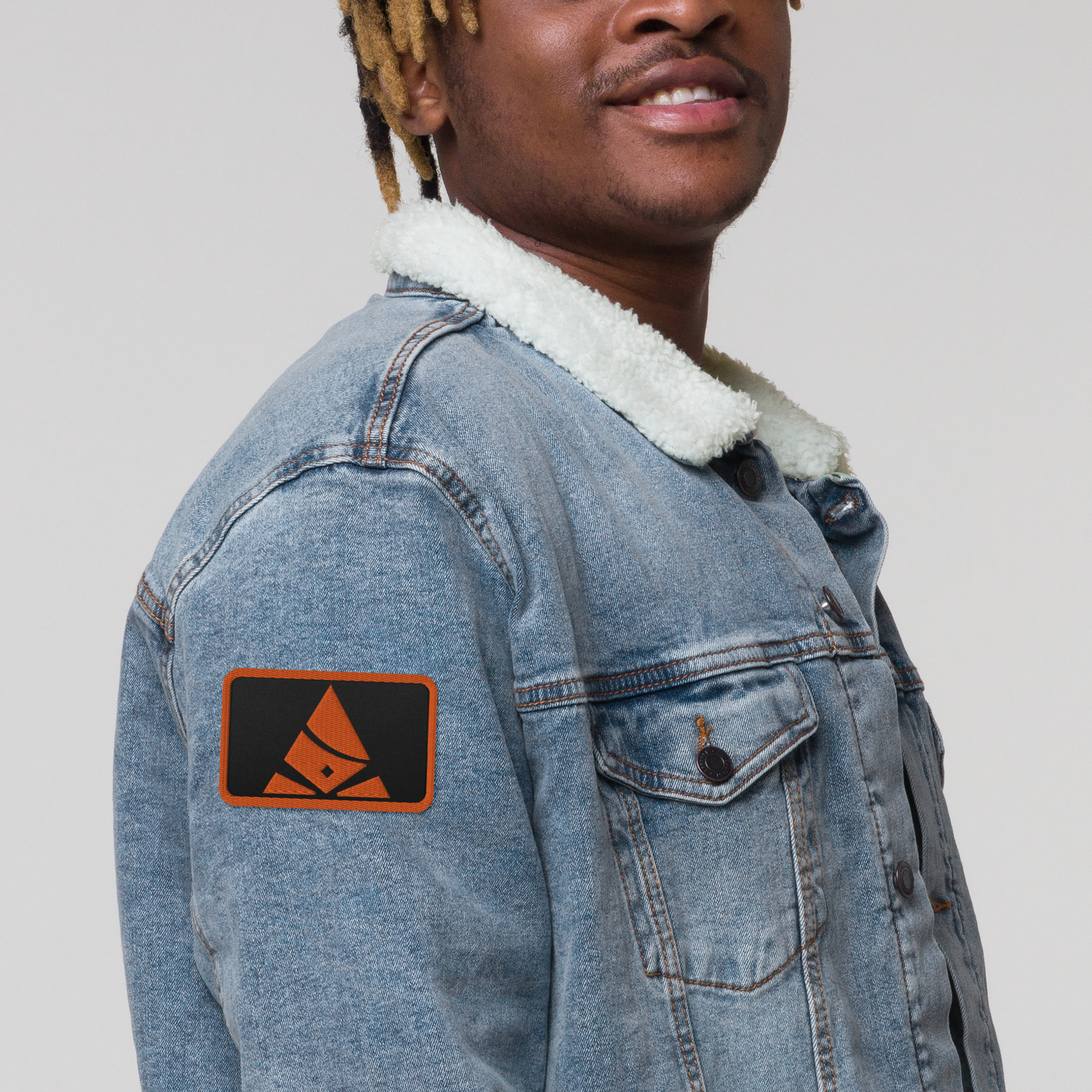 Man wearing jean jacket with embroidered Bank of Zaonce logo in orange right view