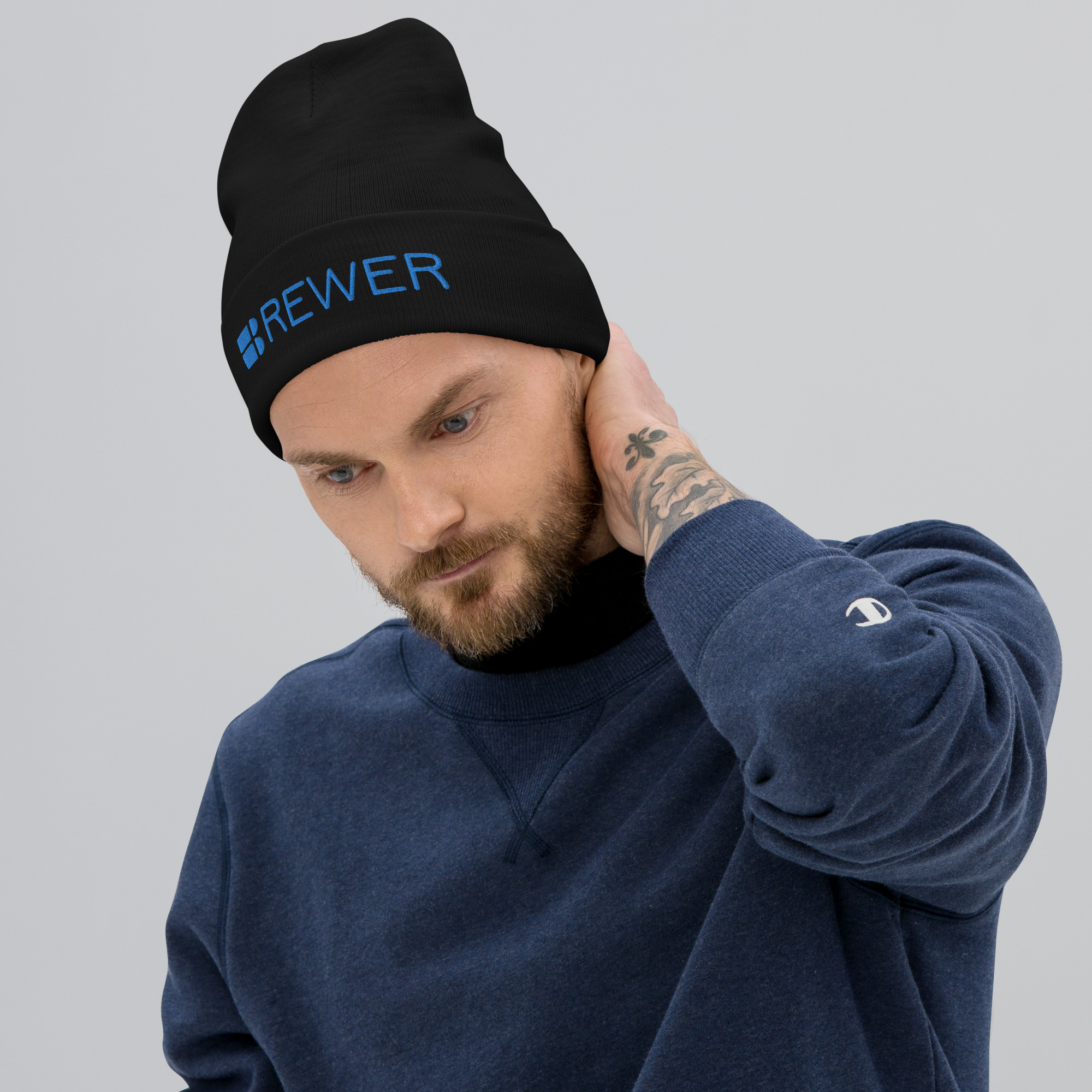 Man wearing black beanie with Brewer Corporation logo embroidered on the front in blue